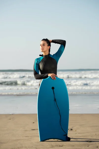 Портрет серфінгу жінки з бодібілдингом проти моря — стокове фото