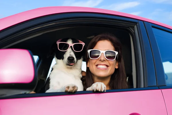 Donna divertente con cane in auto rosa — Foto Stock