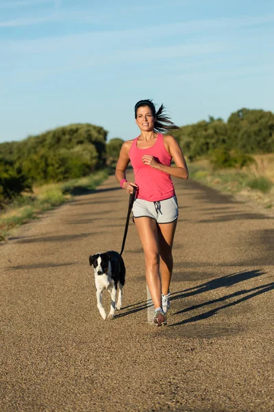 Giovane donna sportiva e cane in esecuzione — Foto Stock