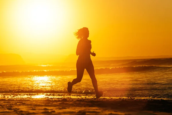 Frau läuft bei Sonnenuntergang am Strand — Stockfoto