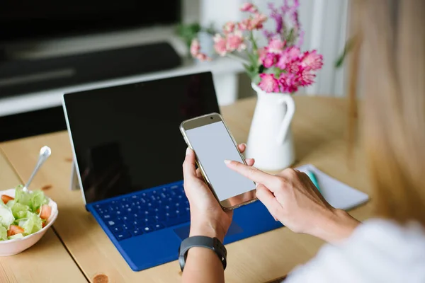 Donna che utilizza smartphone e lavora a casa sul computer portatile — Foto Stock