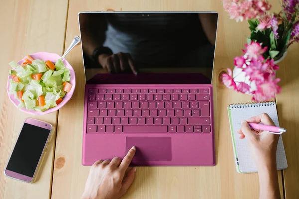 Vista dall'alto della donna che utilizza computer portatile e prendere appunti su un no — Foto Stock