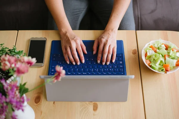 Primo piano delle mani femminili che digitano sulla tastiera del computer portatile a casa — Foto Stock