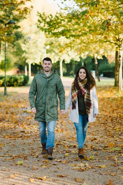 Νεαρό ζευγάρι ευτυχισμένο το φθινόπωρο με τα πόδια στο πάρκο — Φωτογραφία Αρχείου