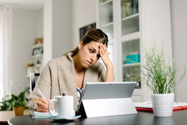 Mujer estresada en problemas trabajando desde casa con la tableta — Foto de Stock