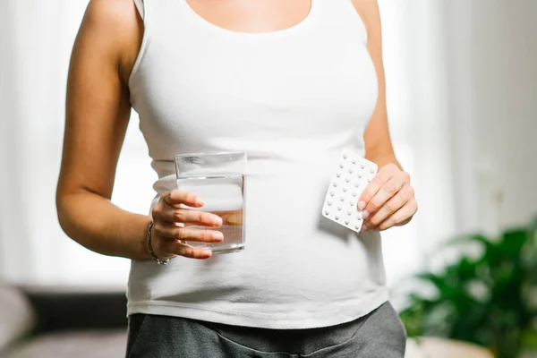 Gravid kvinna som håller folsyra blister och glas vatten — Stockfoto