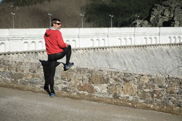Atleta treinando ao ar livre ao lado de uma barragem de montanha — Fotografia de Stock