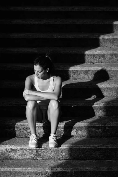 Atleta cansada feminina sentada nas escadas — Fotografia de Stock