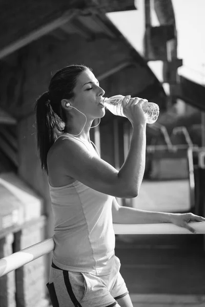 Female athelte resting and drinking water — Stock Photo, Image