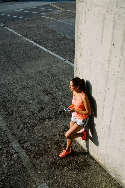 运动的妇女使用智能手机短信在城市锻炼 r — 图库照片