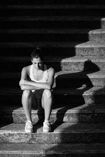 Atleta feminina sentada nas escadas para descansar — Fotografia de Stock