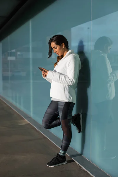 Спортивная женщина с мобильным телефоном во время тренировочного отдыха — стоковое фото