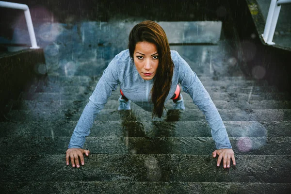 Mujer haciendo flexiones en las escaleras en invierno día lluvioso — Foto de Stock