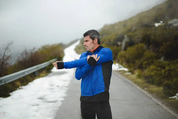 Treinamento de atleta e corrida no inverno na estrada da montanha — Fotografia de Stock