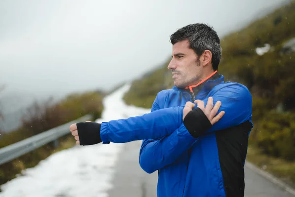 Спортсмен тренируется и бегает зимой по горной дороге — стоковое фото