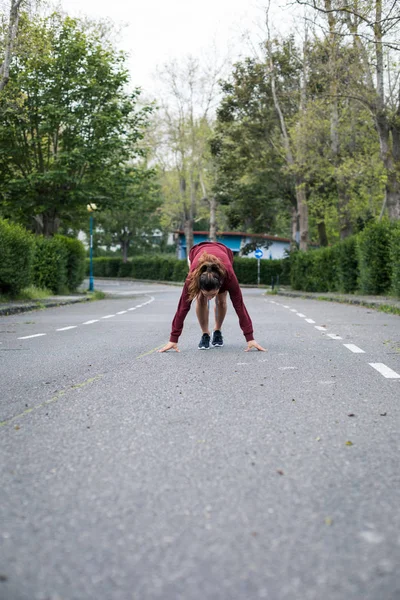 若い女性アスリートは爆発的な春の準備ができている都市郊外の道路上で実行 — ストック写真