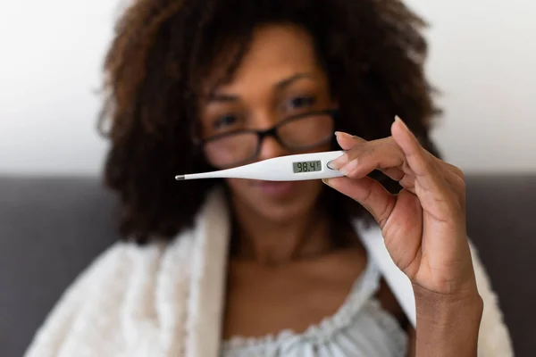 Woman shows a thermometer with normal body temperature after overcoming a virus infection and quarantine. Coronavirus infeted patient cured.