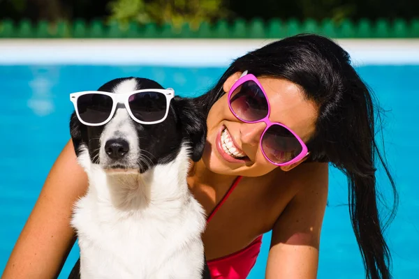 幸せな女とかわいい犬サングラスとスイミング プールで夏休みの楽しい — ストック写真