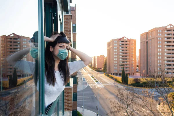 Ffp2フェイスマスクを持つ絶望的な女性は Covid 19危機に対する隔離中に窓の外を覗きます 家の概念にとどまる 監禁下の空虚な街 スペインのバジャドリード — ストック写真