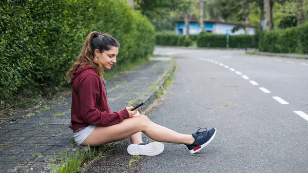 スマートフォンアプリでワークアウトの目標をチェックするために休息を取っているスポーティ若い女性 — ストック写真
