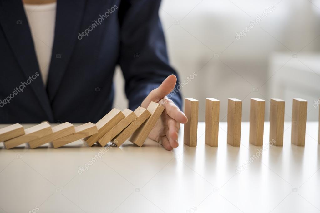 Hand stopping falling blocks on table