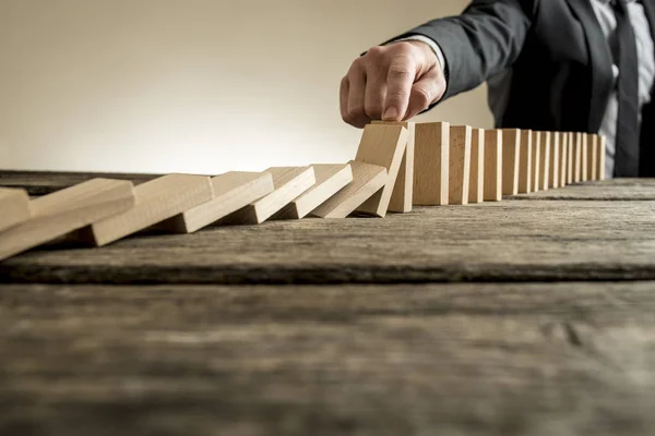 Üzletember megállás csökkenő domino darab kézzel — Stock Fotó