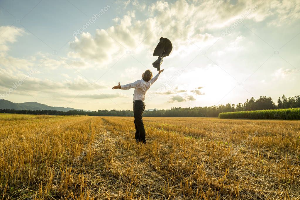 Businessman in field throwing jacket in air