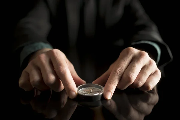 Бизнесмен держит компас на черном столе — стоковое фото