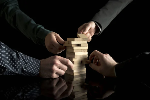 View of four male hands pulling pieces from tower — Stock Photo, Image