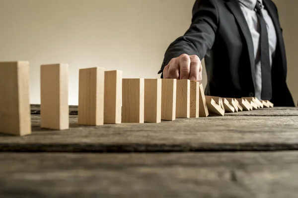 Businessman stopping domino effect with his finger — Stock Photo, Image