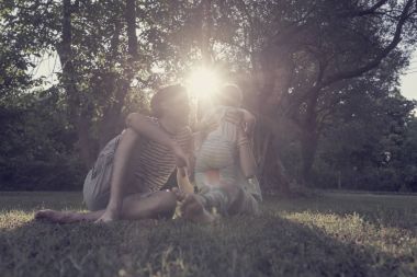 Anne kendi toddl tutan iken çim bir parkta oturan Çift