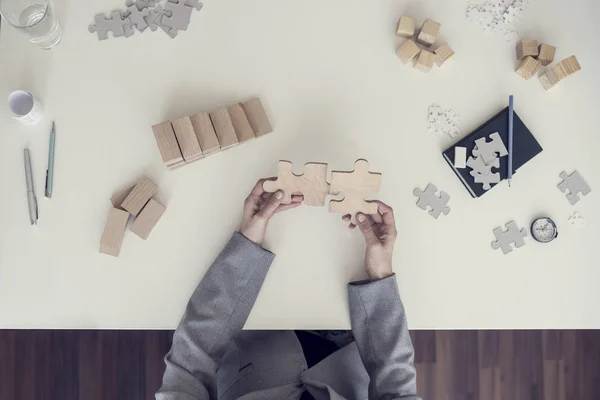 Vue du dessus des mains féminines assemblant deux pièces de puzzle en bois — Photo