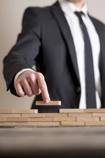 Zakenman in business suit plaatsen houten blokken op tafel — Stockfoto