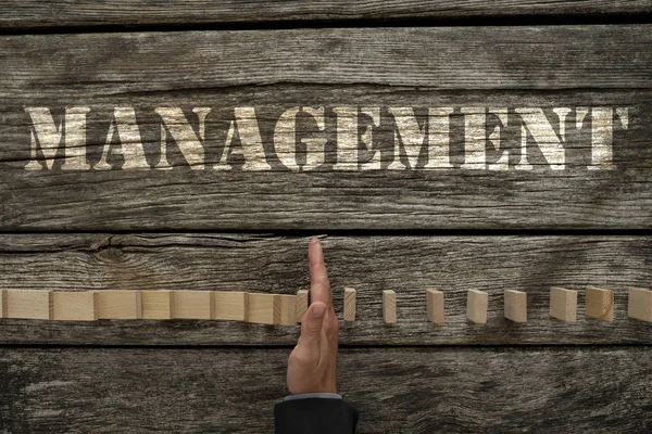 Falling dominos on a desk with management text — Stock Photo, Image