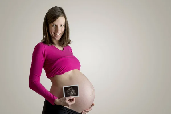 Pregnant woman showing ultrasound picture of embryo baby — Stock Photo, Image