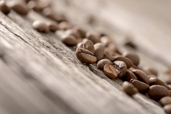 Geröstete Kaffeebohnen liegen auf einer alten rustikalen Holzoberfläche — Stockfoto
