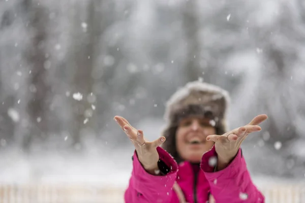 Mulher chegando com ambas as mãos para pegar flocos de neve caindo — Fotografia de Stock