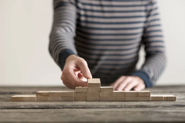 L'uomo costruisce una piramide di blocchi di legno — Foto Stock