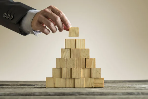 Businessman making a pyramid with empty wooden cubes — Stock Photo, Image