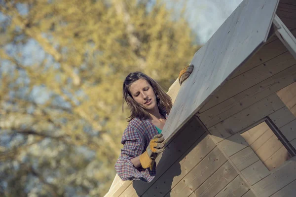 Femme mettant une planche de bois sur le toit du hangar de jardin — Photo