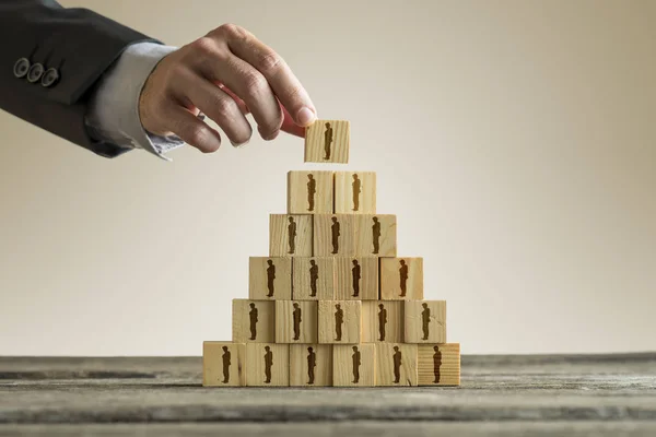 Homme d'affaires construisant une pyramide de blocs de bois avec des gens silhou — Photo