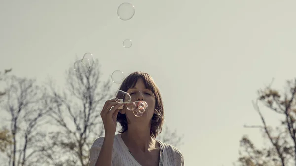 Vue de face d'une femme soufflant des bulles de savon à l'extérieur — Photo