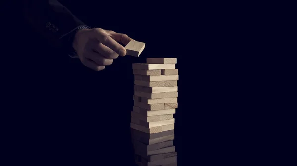 Male hand creating or building a tower of many wooden blocks ove — Stock Photo, Image