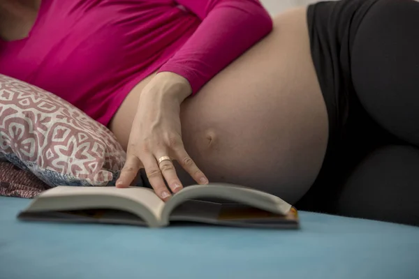 Närbild av en gravid kvinna läser en bok — Stockfoto