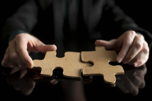 Üzletember-fekete öltöny kezében két puzzle-darab megfelelő — Stock Fotó