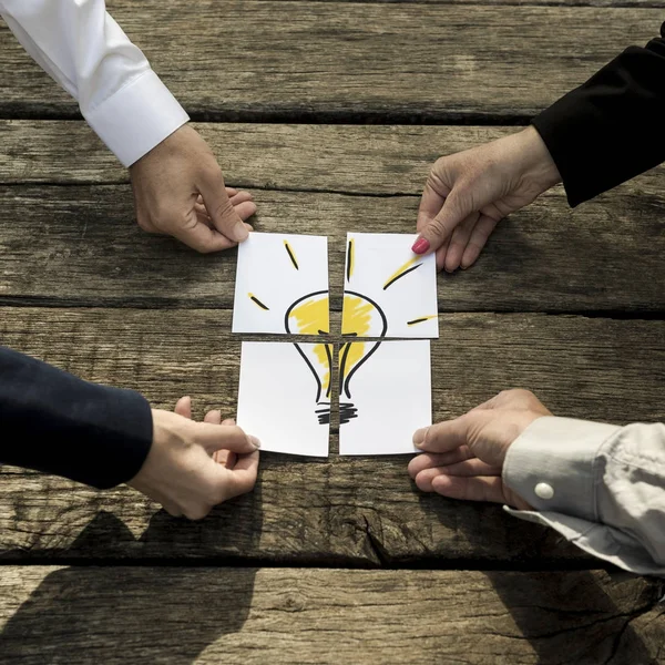 Vier Geschäftsleute stellen eine Glühbirne zusammen — Stockfoto