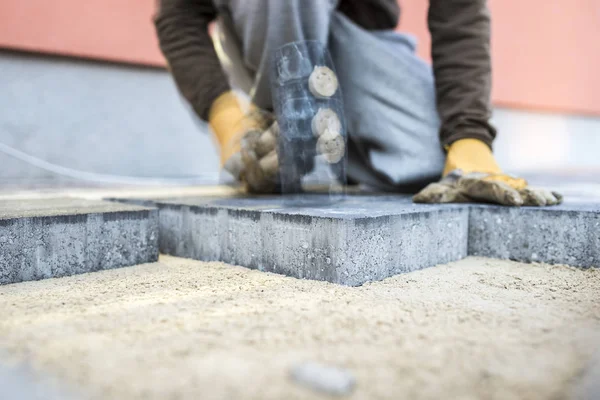 Bauarbeiter stampft eine neue Pflasterplatte oder Ziegel mit Bewegungsunschärfe ab — Stockfoto