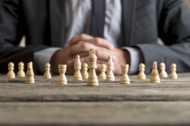 Beyaz satranç önünde giyen takım elbise oturan adam