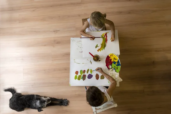 Bambini che dipingono sul tavolo con cane sdraiato sul pavimento — Foto Stock