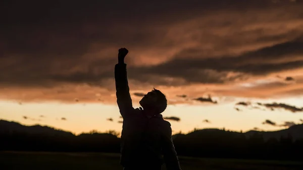 Hombre levantando su puño contra la puesta del sol cielo — Foto de Stock